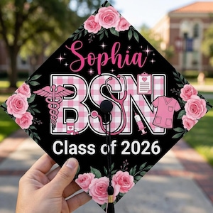 May include: Black graduation cap with pink floral accents and the name "Sophia" in cursive. The letters "BSN" are in a pink and white checkered pattern, with medical symbols. The text "Class of 2026" is also included.