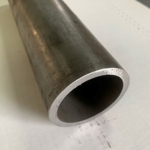 May include: A close-up of a round, metal pipe. The pipe is silver in color and has a smooth, polished surface.