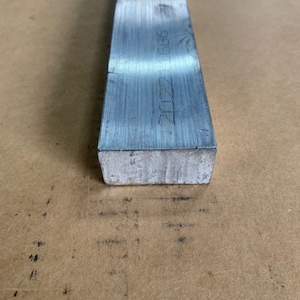 May include: A silver metal bar with the text "2022 565" etched on the side.