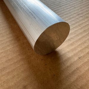 以下が含まれることがあります： ブラッシュ仕上げの銀色の円筒形の金属棒。棒の端は角度が付けられており、中実の円形断面が現れています。棒は明るい色の金属でできています。