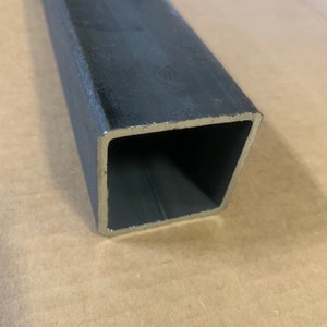 May include: A close-up of a black metal square tube. The tube is hollow and has a smooth, polished finish.