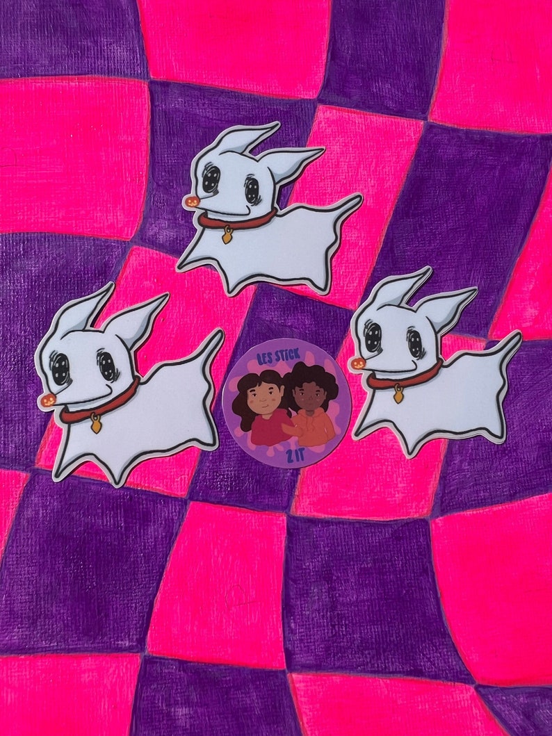 May include: Three white cartoon dog stickers with black eyes and red collars on a pink and purple checkered background. A round sticker with two cartoon girls and the text "Les Stick 217" is in the center.