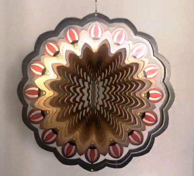 May include: A decorative metal wind spinner with a layered design featuring red and white hot air balloons. The spinner has a black metal frame and is designed to rotate in the wind.