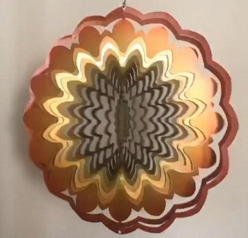 May include: A multi-layered, circular wind spinner with a swirling pattern. The spinner is made of metal and has a copper, gold, and brown color scheme.
