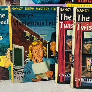 May include: Four Nancy Drew mystery books with colorful covers. The books are titled "The Clue of the Tapping Heel", "Nancy's Mysterious Letter", "The Sign of the Twisted Candles", and "The Twisted Candles".