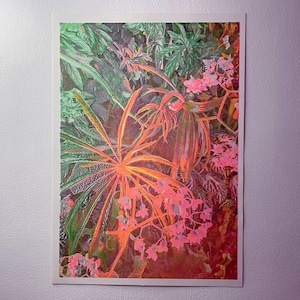May include: A colourful botanical print depicting tropical plants. The artwork shows a central orange plant with radiating leaves, surrounded by green foliage and delicate pink flowers. The print is framed in white.