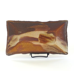 Op de afbeelding: Een rechthoekige serveerschaal van keramiek met een bruine en beige glazuur. De schaal heeft een licht onregelmatige vorm en een ruwe textuur.