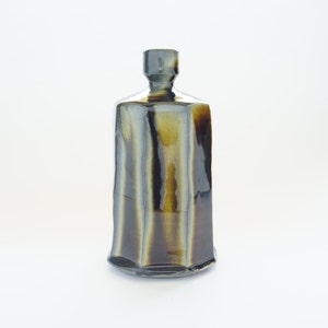 May include: A dark brown and black ceramic vase with a geometric shape and a glossy finish.