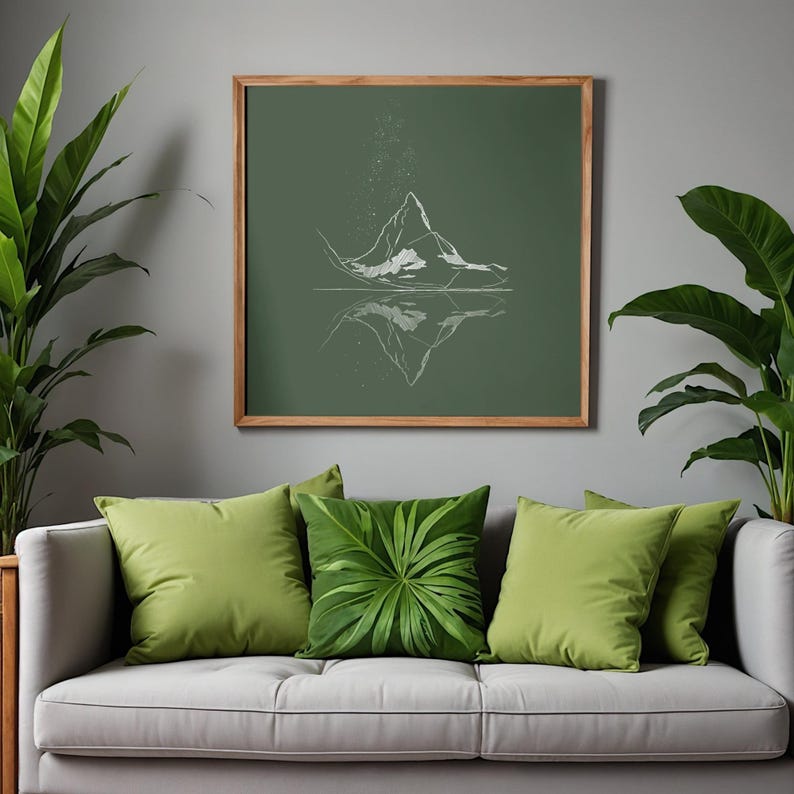 May include: A framed print with a white mountain range design on a dark green background. The artwork is displayed above a grey sofa with green cushions and a leaf-patterned cushion. The room is decorated with green plants.
