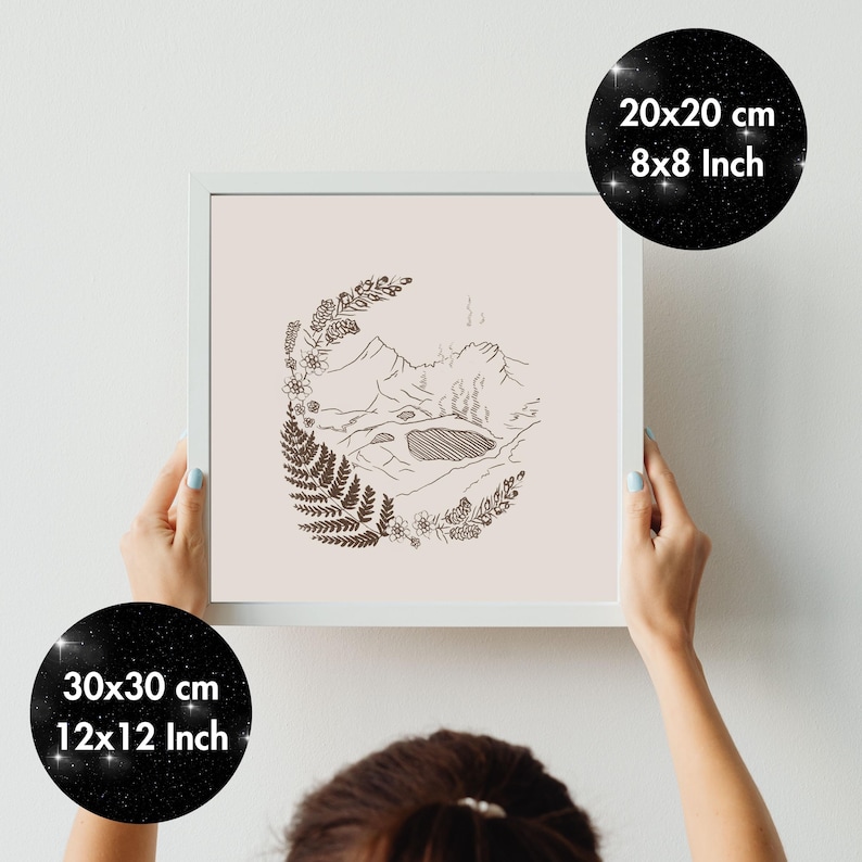 May include: A framed print with a minimalist landscape design in brown ink on a pale pink background. The artwork shows mountains, a lake, and foliage. The frame is white, and the print is available in 20x20 cm and 30x30 cm sizes.