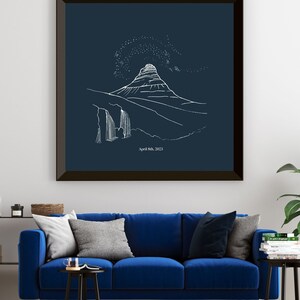 May include: Framed art print featuring a white line drawing of a mountain landscape with a waterfall and starry sky on a navy blue background. The date "April 8th, 2023" is printed at the bottom. The artwork is displayed above a blue sofa.