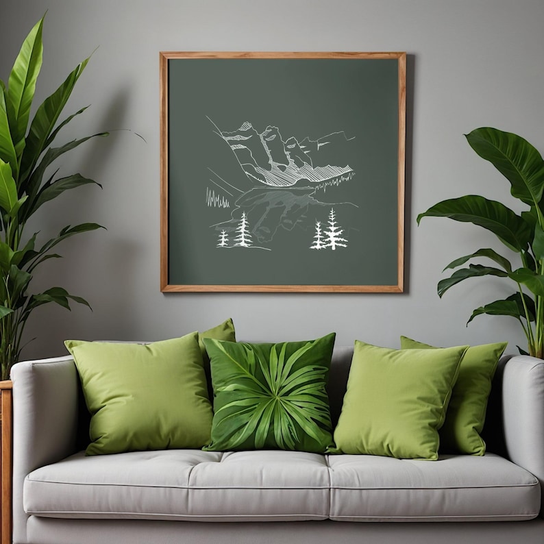 May include: A framed print with a white line drawing of mountains and trees on a dark green backdrop. The print hangs above a grey sofa with green cushions, one with a leaf pattern. Potted plants are positioned on either side of the sofa.
