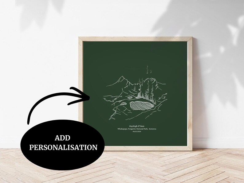 May include: A framed print with a white line drawing of a mountain scene on a dark green background. The print has text at the bottom and is in a light wood frame. The words "ADD PERSONALISATION" are in a black oval.