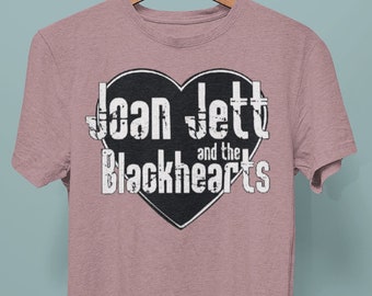 May include: A heather pink t-shirt with a black heart graphic featuring the text "Joan Jett and the Blackhearts" in white.