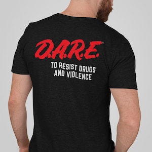 May include: Black t-shirt with the red text "D.A.R.E." above the words "TO RESIST DRUGS AND VIOLENCE" in white. The shirt is made of a soft material and has short sleeves.