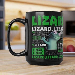 Puede incluir: Taza de cerámica negra con un gráfico de lagarto verde y blanco y la palabra "LIZARD" en letras verdes grandes. La taza también presenta el texto "Lizard, Lizard" y una ilustración de lagarto de dibujos animados.