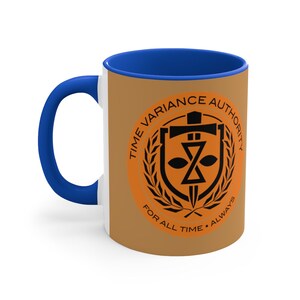 May include: A white ceramic coffee mug with a blue rim. The mug has a brown background with an orange circle in the center. The circle features a black and white logo with the text "Time Variance Authority" and "For All Time. Always".