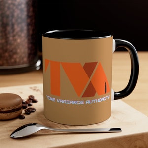 May include: A brown ceramic mug with a black rim and handle. The mug features the Time Variance Authority logo in orange and red with the text "TIME VARIANCE AUTHORITY" below.