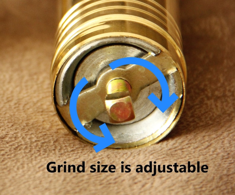 May include: Close-up of a gold pepper grinder with a visible adjustment mechanism. The grind size is adjustable by turning the knob on the side of the grinder.  "Grind size is adjustable" is printed on the bottom of the image.