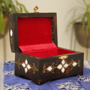 May include: A wooden box with a red velvet interior and intricate white and gold inlay. The box is open and has a brass latch.