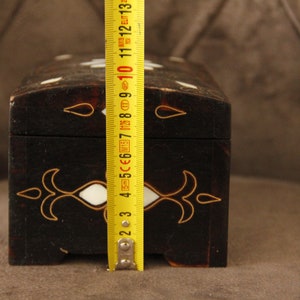 May include: A black wooden box with white and gold inlay. The box is 7 inches long and has a hinged lid.