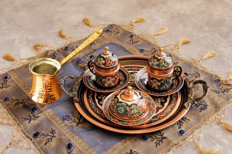Pode incluir: Uma bandeja de servir de cobre com tr&ecirc;s x&iacute;caras de caf&eacute; de cobre ornamentadas e um cremer a condizer. A bandeja e as x&iacute;caras s&atilde;o decoradas com padr&otilde;es florais coloridos.