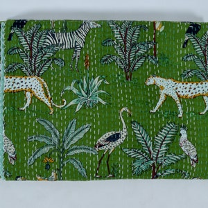 Puede incluir: Una colcha kantha verde con un borde blanco. La colcha presenta un patrón repetido de cebras, leopardos, flamencos y palmeras.
