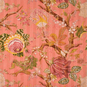 May include: A pink fabric with a floral pattern. The pattern features large pink flowers with yellow centres, green leaves, and brown branches. The fabric has a quilted texture.