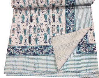 May include: A white kantha quilt with a blue and white fish pattern. The quilt is folded in half and has a blue and white striped border.