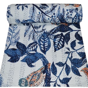 Op de afbeelding: Een wit kantha-dekbed met een blauw bloemenpatroon en vogels. Het dekbed is met de hand gestikt en heeft een traditioneel Indiaas ontwerp.