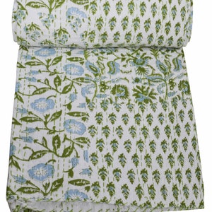 Op de afbeelding: Een wit katoenen dekbed met een groen en blauw bloemenpatroon. Het dekbed is dubbelgevouwen en heeft een gestikte textuur.