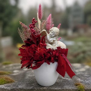 Grave arrangement with angel, chrysanthemums, and red/pink ribbon
