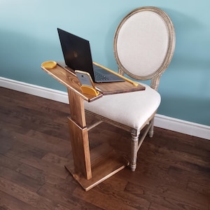 May include: A dark wood C-shaped side table with a rectangular top, a vertical support post, and a flat base. The table features a yellow circular coaster insert and a yellow phone stand holding a smartphone, with a black laptop placed on top.