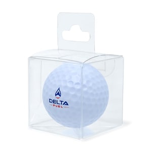 Puede incluir: Una pelota de golf blanca con el logotipo "DELTA - FUEL" en azul y rojo, dentro de una caja de pl&aacute;stico transparente con una pesta&ntilde;a para colgar. La pelota tiene una superficie con hoyuelos.