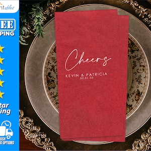 May include: Red paper napkins with the text "Cheers" in white script font, followed by "Kevin & Patricia" and the date "02.01.25" in a smaller font.
