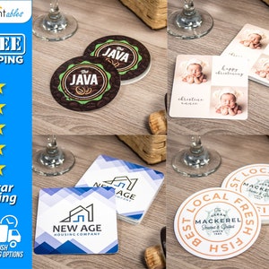 May include: A collection of custom coasters and cards. Coasters feature "The Java" logo, "New Age Housing Company" logo, and a "Best Local Fresh Fish" design. Cards display baby photos with "Happy Christening" text. The image is on a wooden surface.