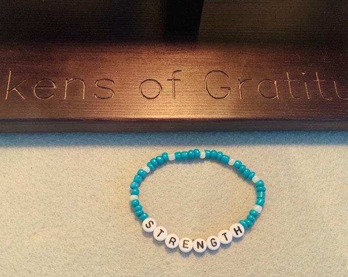 Turquoise colored personalized beaded stretch bracelet with “strength “ beads