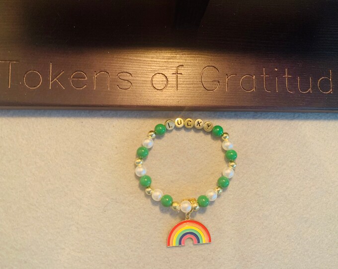 St Patricks Beaded Bracelet with “lucky” written in gold letters, rainbow charm