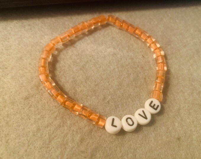 Sparkly peach colored personalized beaded stretch bracelet with “love“ beads