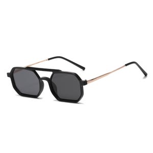 Puede incluir: Gafas de sol negras con doble puente y lentes octogonales. Las monturas son negras, con varillas doradas y lentes gris oscuro. Diseño geométrico moderno.
