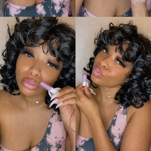 May include: Four-panel image of a person applying lip gloss. The person has dark curly hair and is wearing a pink and black tie-dye top. The lip gloss tube is light purple with a white applicator.