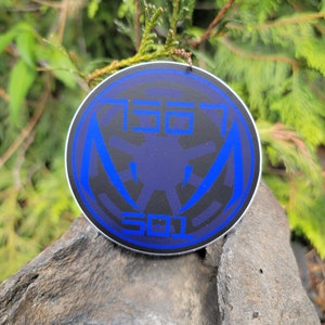 May include: A round sticker with a blue and black design. The sticker features a stylized symbol with the text "501" and "150" on either side.