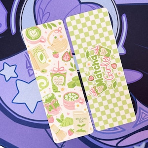 May include: Two decorative bookmarks with matcha tea illustrations. One bookmark features a white background with matcha tea and strawberry graphics. The other has a green and white checkered pattern with the text "Matcha Girly".