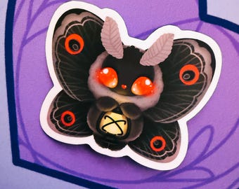 May include: A sticker featuring a cartoon moth with black wings, red eyes, and a fluffy white face. The moth is holding a small lantern. The sticker has a white border and is set against a purple background with a decorative design.