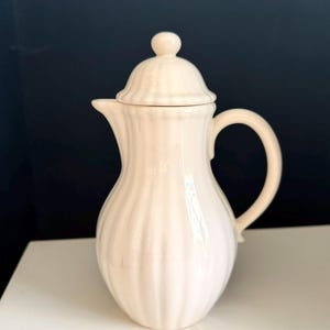 Op de afbeelding: Een set van drie keramische mokken met een gespikkelde, matte afwerking. De mokken zijn in crème, lichtgrijs en donkergrijs. Elke mok heeft een eenvoudig, minimalistisch ontwerp en een afgeronde handgreep.