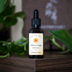 May include: A dark amber glass bottle with a black dropper top. The label reads "California Poppy Herbal Extract" with a flower illustration. The bottle is 1 fl oz. and is labeled "Handmade on Maui".
