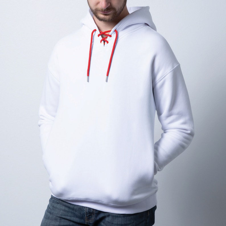 May include: White hoodie with red drawstring laces. The hoodie has a kangaroo pocket and a relaxed fit.