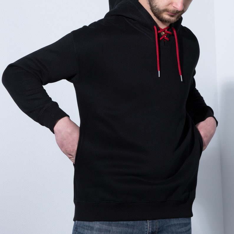 May include: A black hooded sweatshirt with a red lace-up detail at the neckline.