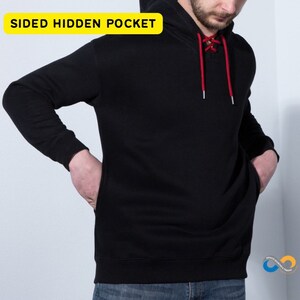 May include: Black hoodie with a drawstring neckline and a kangaroo pocket. The hoodie has a red lace-up detail at the neckline and the text "SIDED HIDDEN POCKET" in a yellow box.