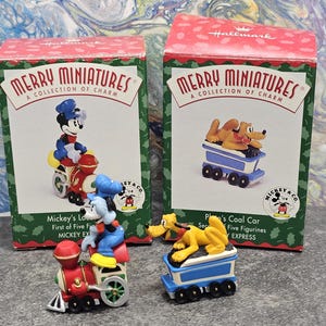 May include: Two Hallmark "Merry Miniatures" boxes featuring Disney characters. One box shows Mickey Mouse on a red train, the other shows Pluto in a blue coal car. The boxes have a red top and green sides.